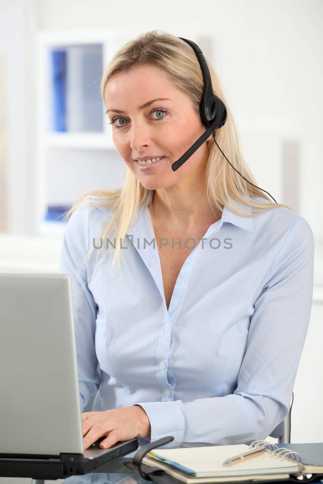 Blond woman in the office with headset on