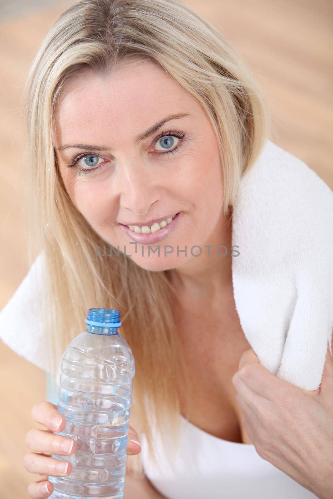 Beautiful blond woman drinking water after exercising