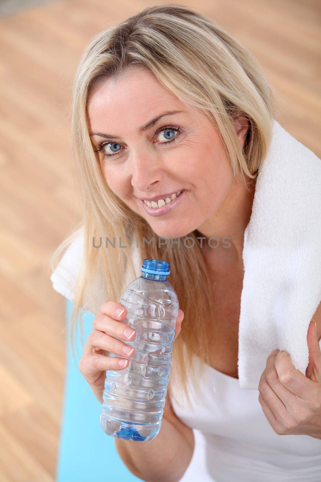 Beautiful blond woman drinking water after exercising