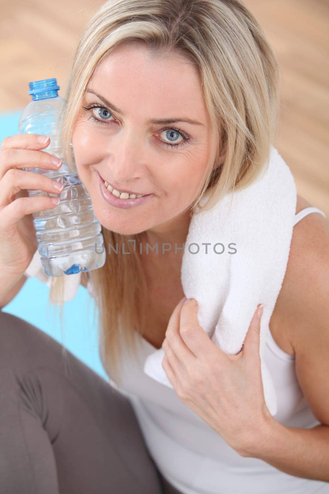 Beautiful blond woman drinking water after exercising