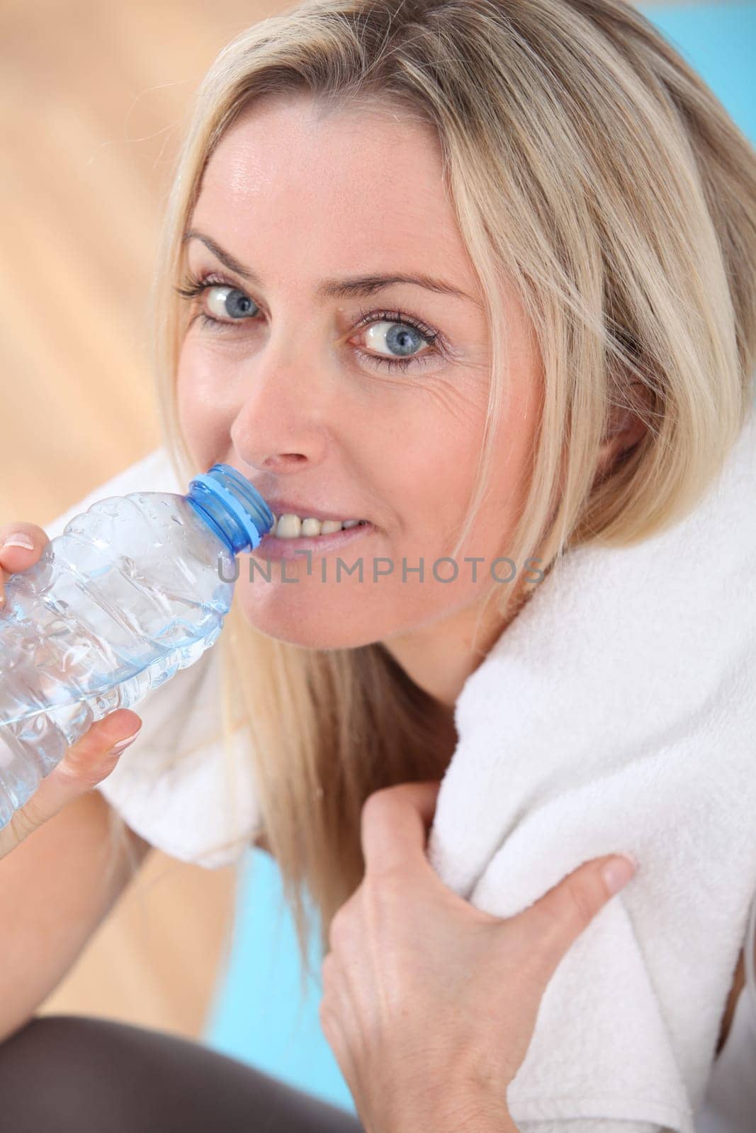 Beautiful blond woman drinking water after exercising