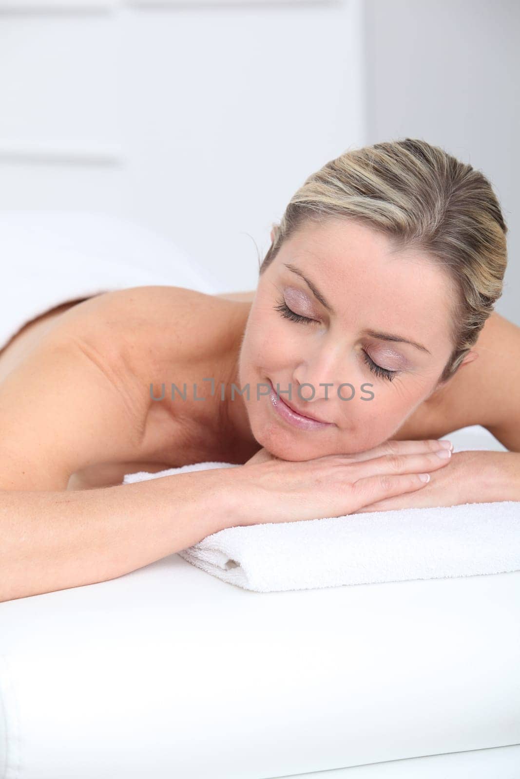 Beautiful adult blond woman on massage bed