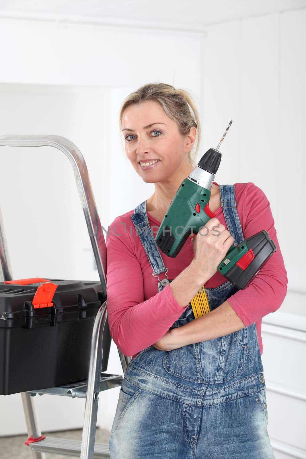 Beautiful blond woman holding electric drill