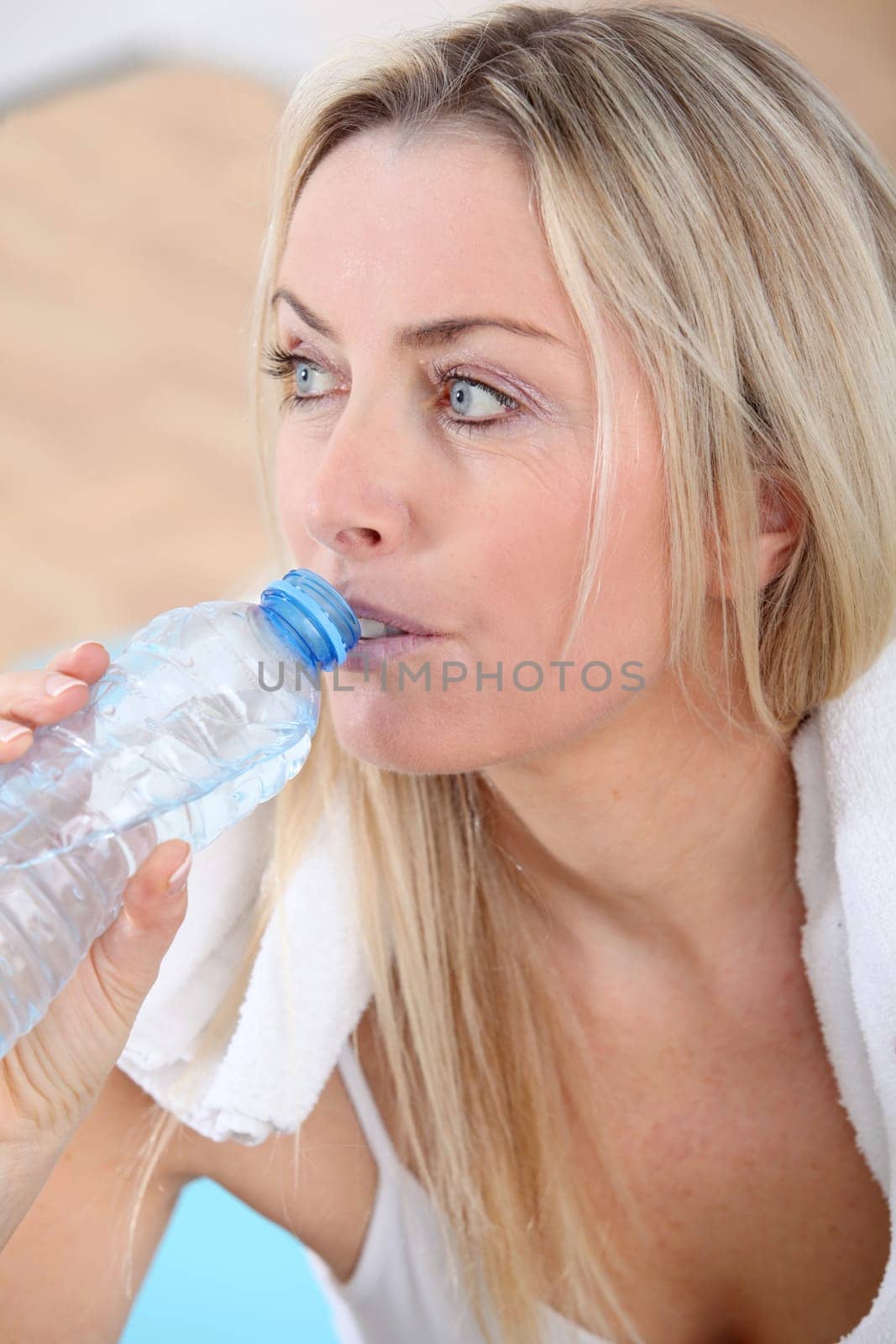 Beautiful blond woman drinking water after exercising