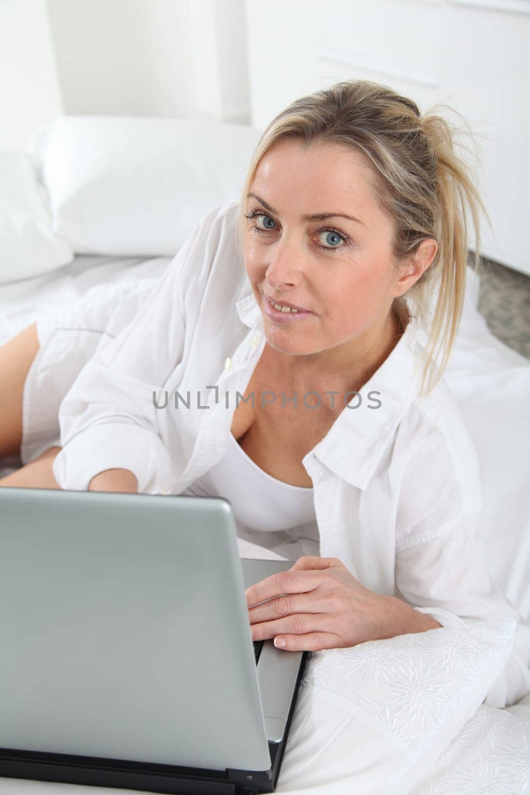 Blond woman with laptop computer in bed