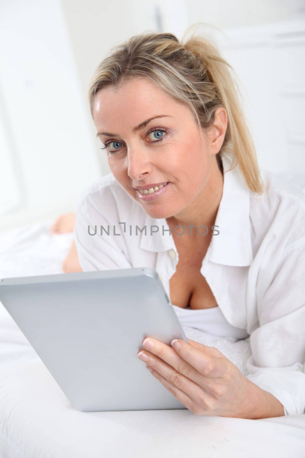 Blond woman using electronic tablet at home