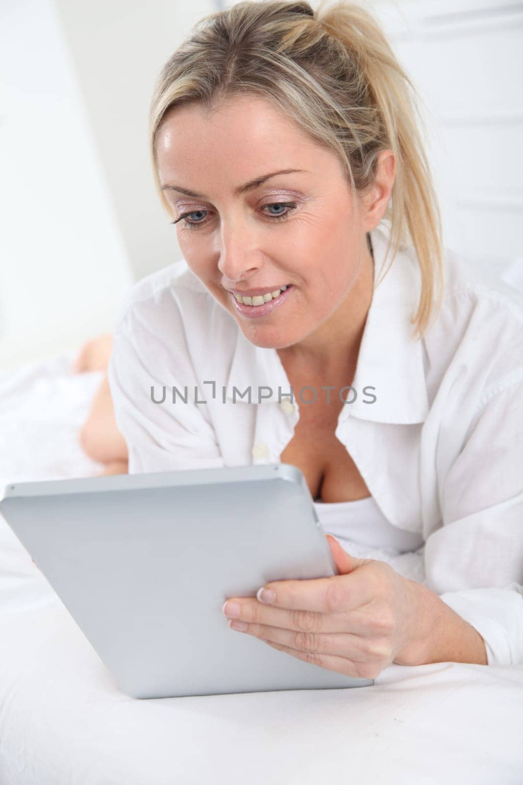 Blond woman using electronic tablet at home