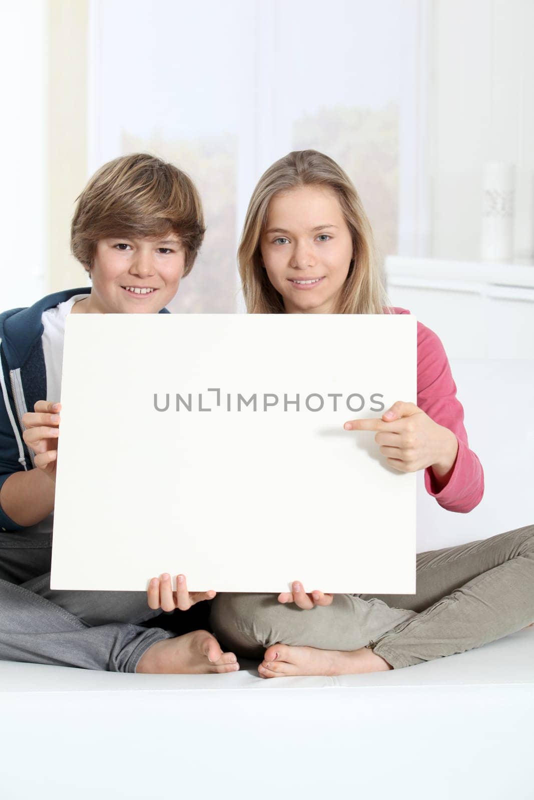 Smiling teenagers sitting in sofa with whiteboard