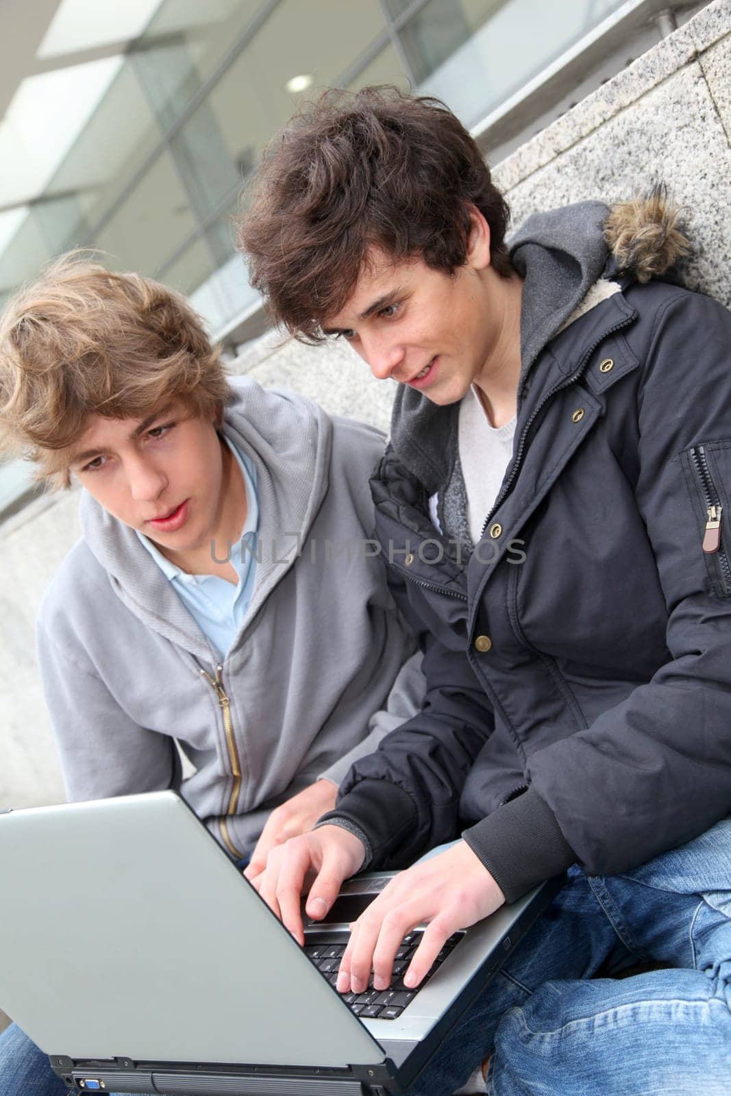 Students with laptop computer outside school building