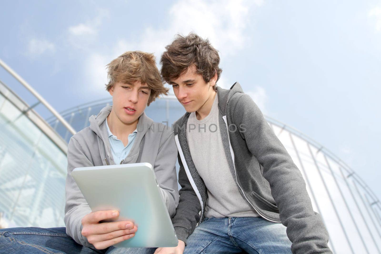 Teenage boys sitting outside with electronic tablet