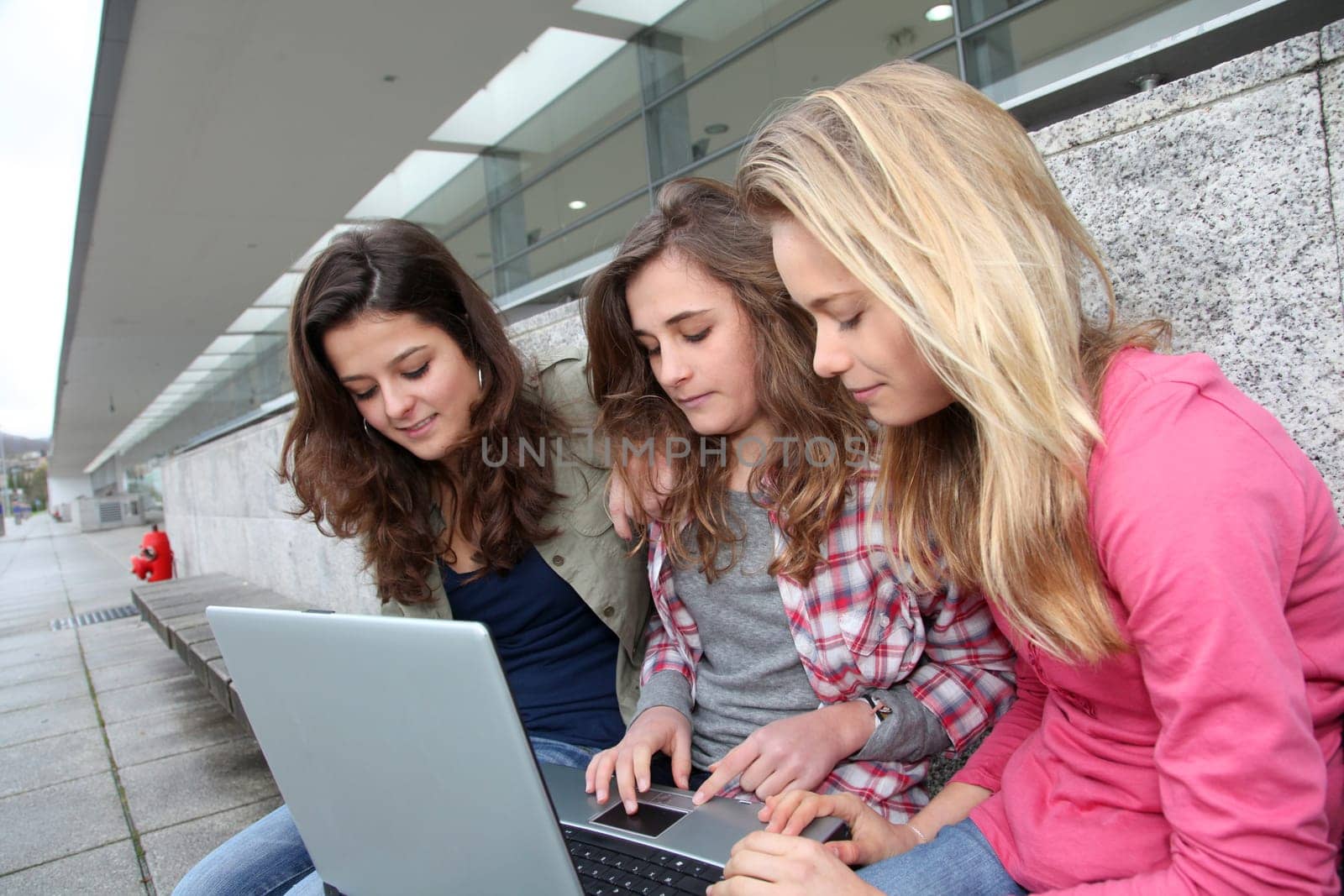 Group of teenage girls with laptop computer in school yard