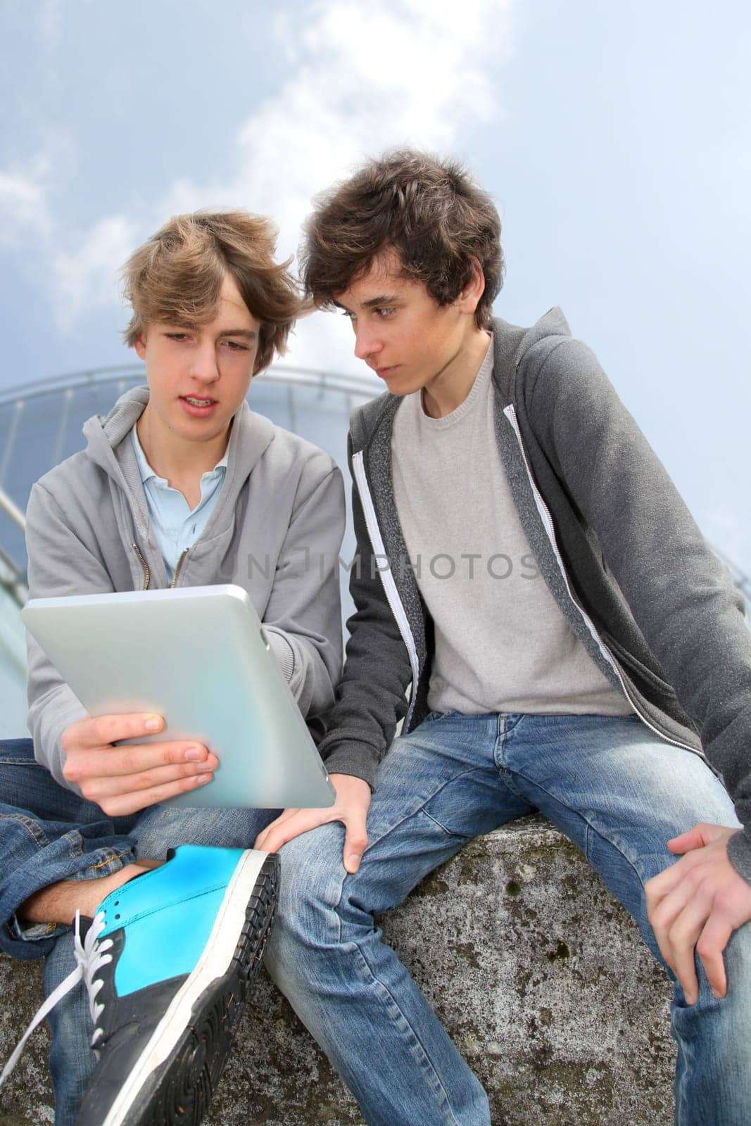 Teenage boys sitting outside with electronic tablet