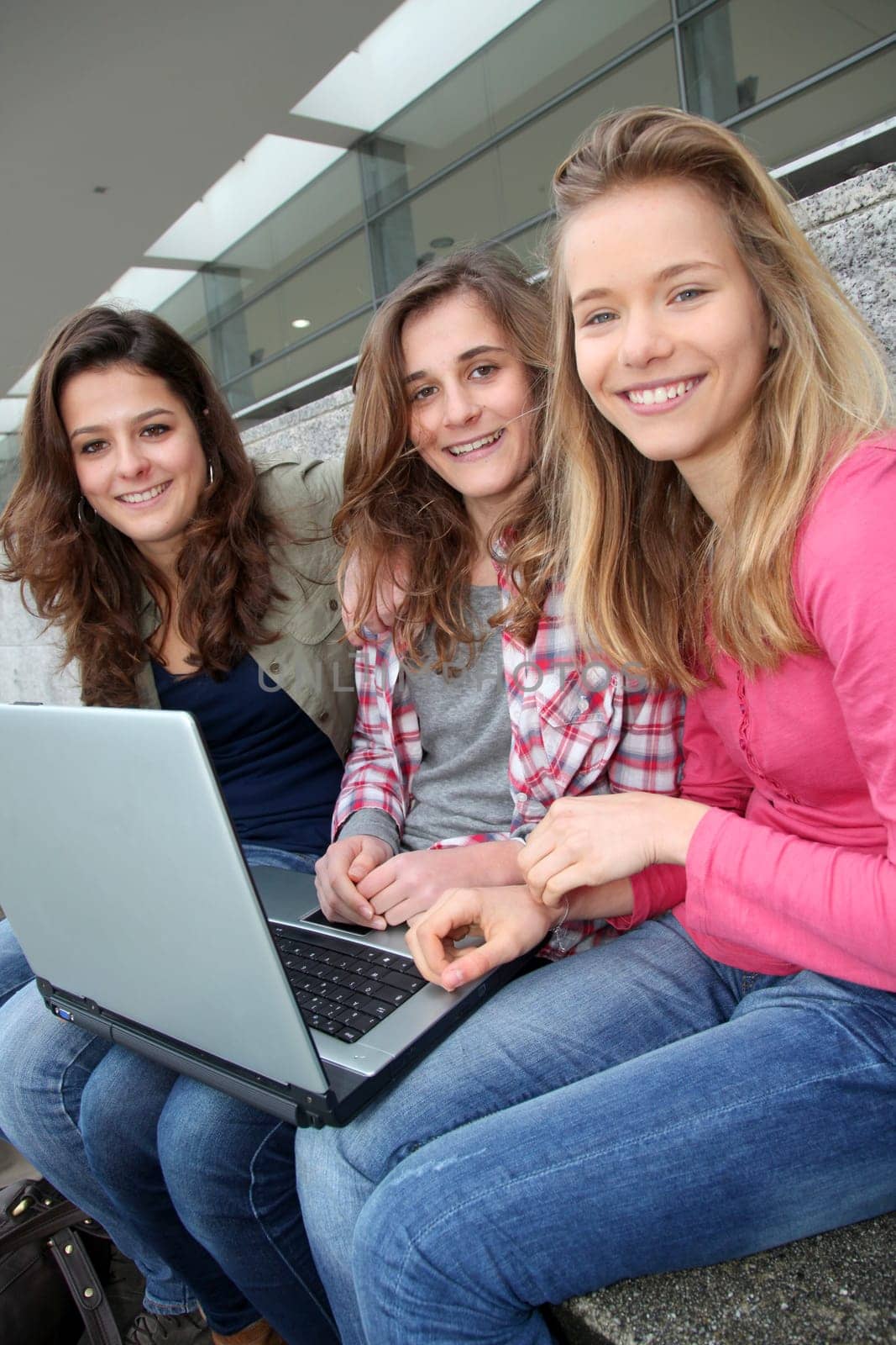 Group of teenage girls with laptop computer in school yard