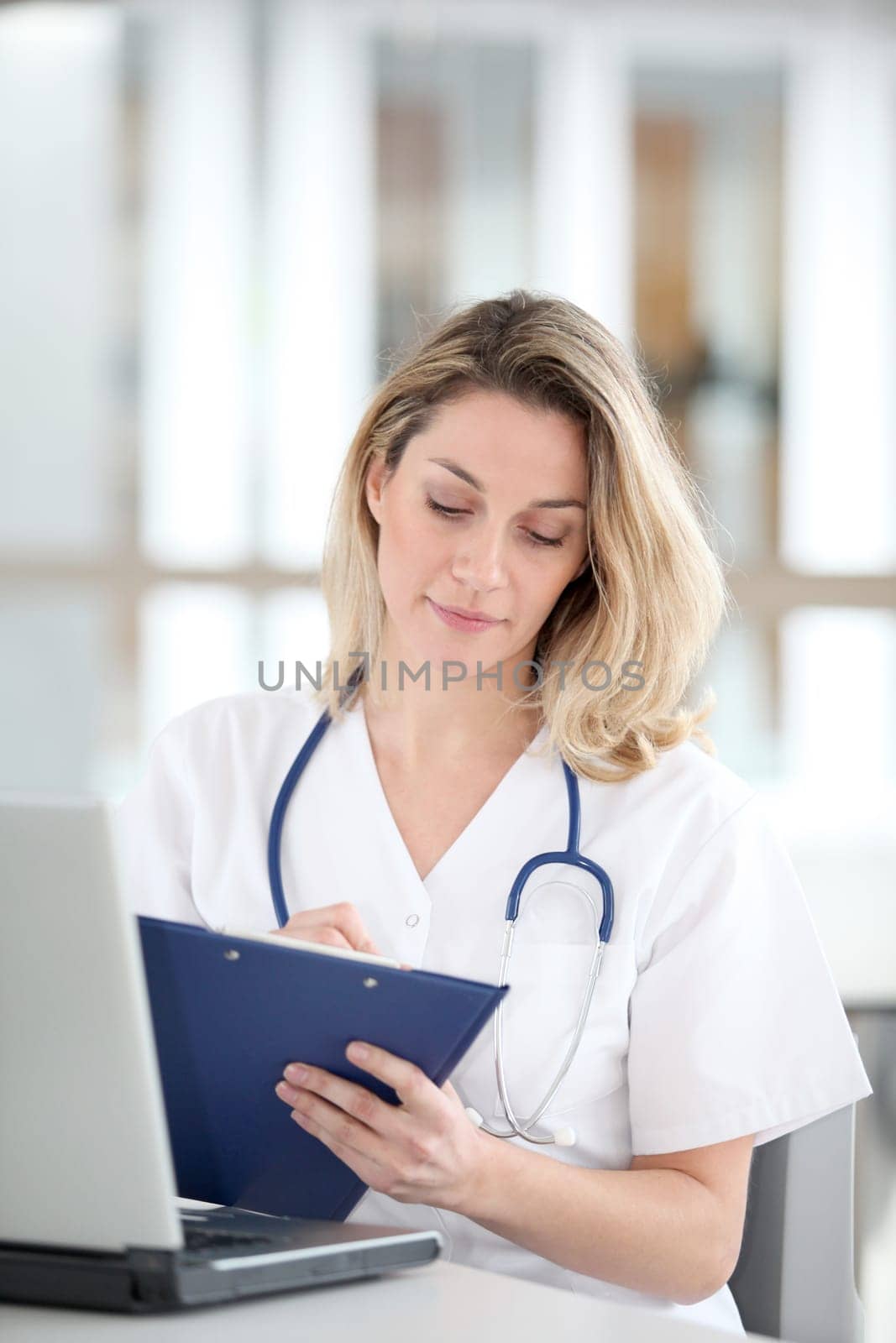 Beautiful nurse in hospital writing on notepad