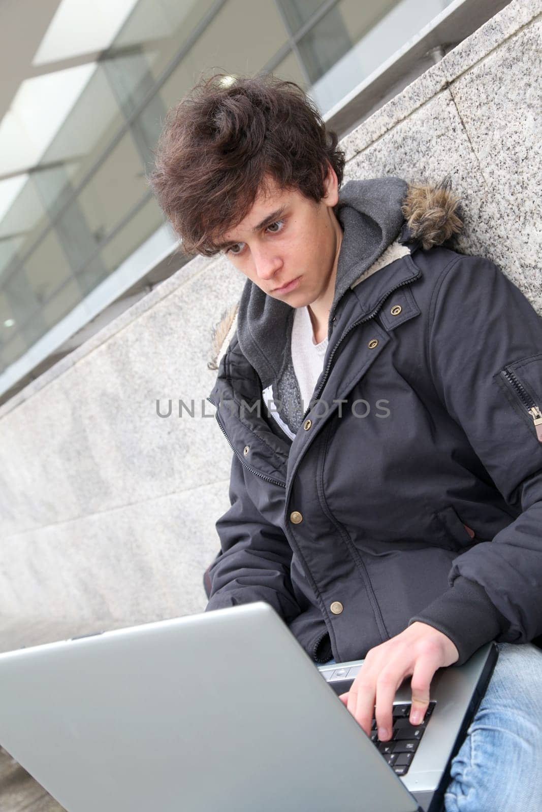 Student with laptop computer outside school building