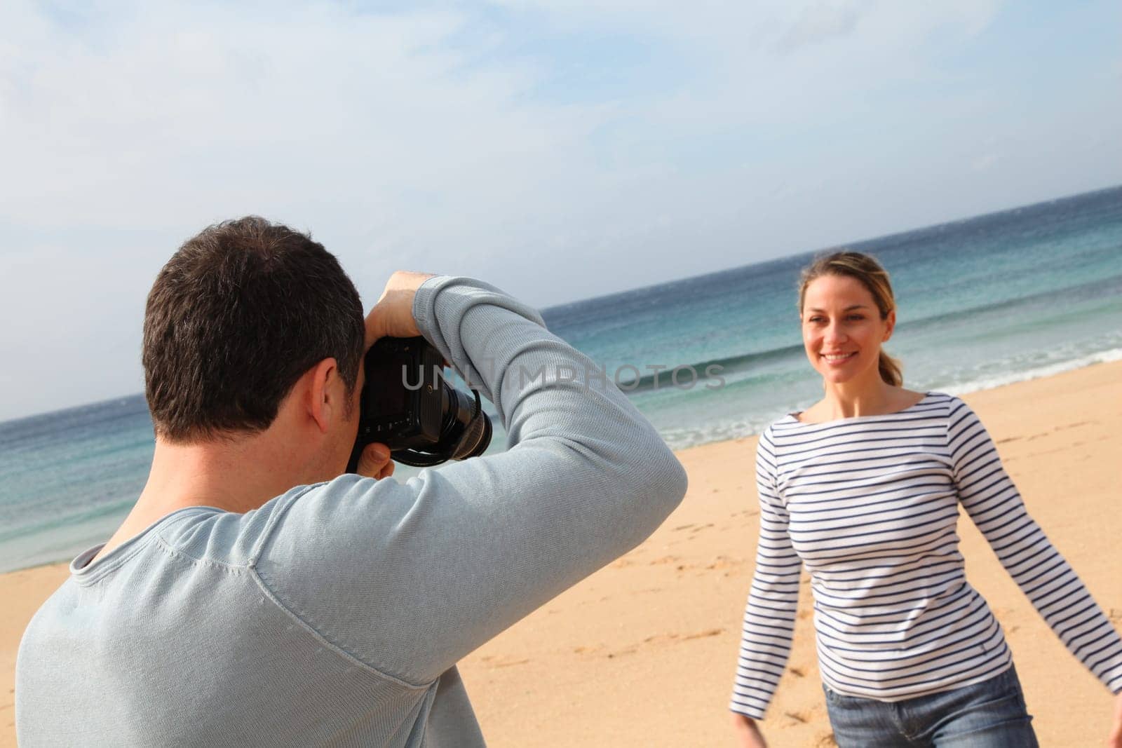 Man taking picture of girlfriend at the beach