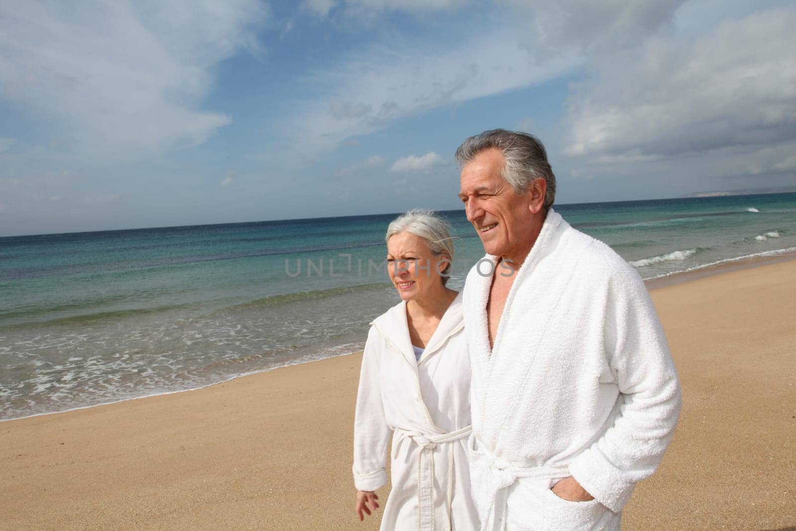 Senior couple in bathrobe at the beach