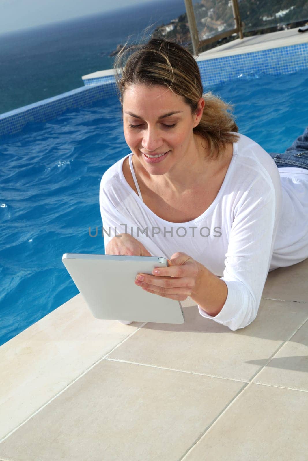 Woman using electronic tablet by swimming pool