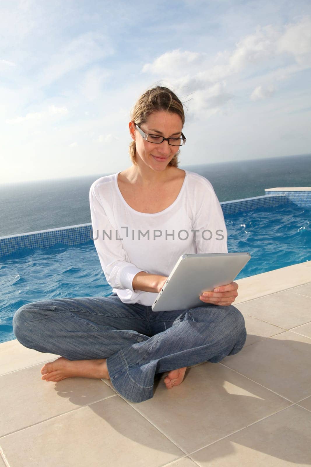 Woman using electronic tablet by swimming pool