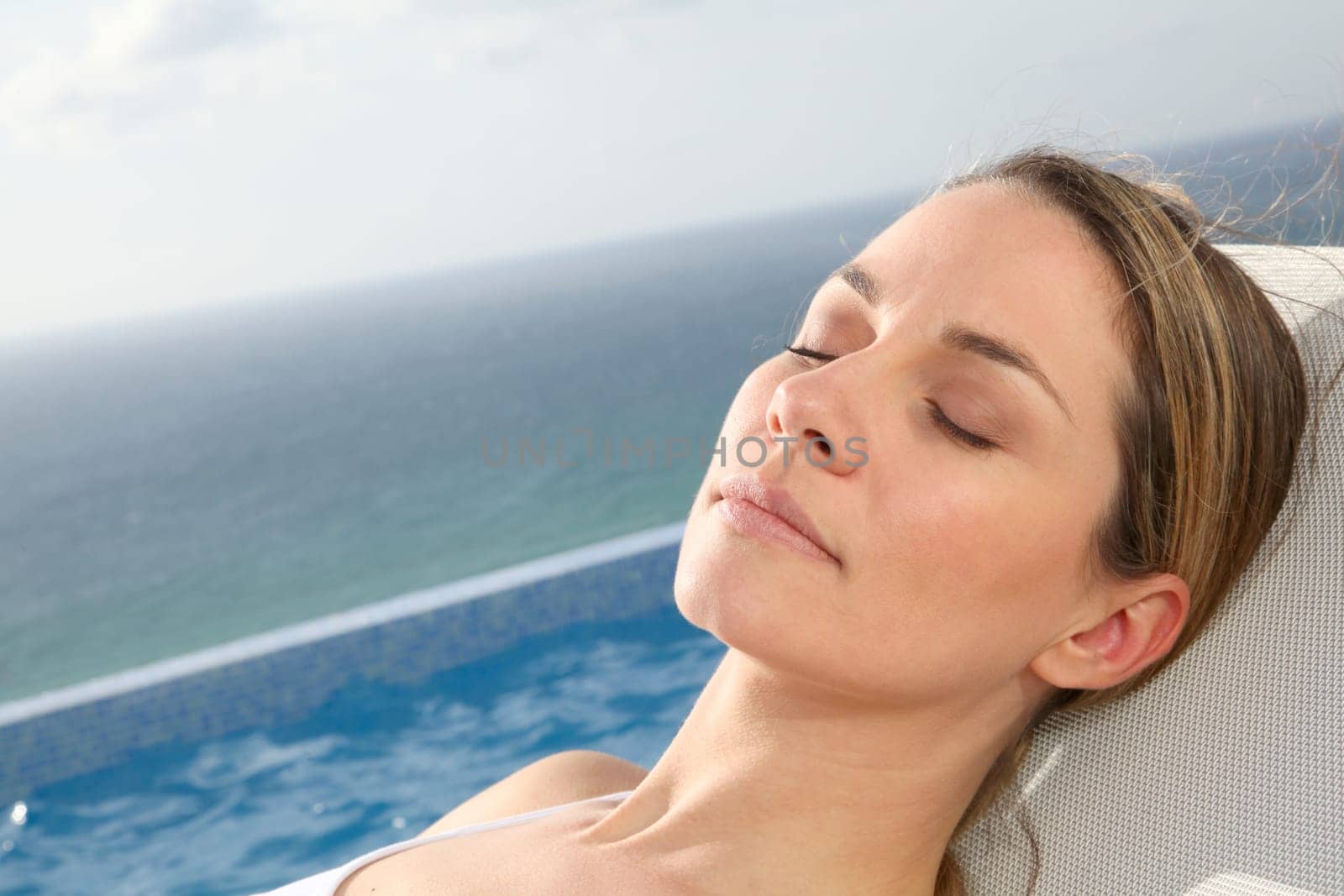 Woman relaxing in deckchair by swimming-pool