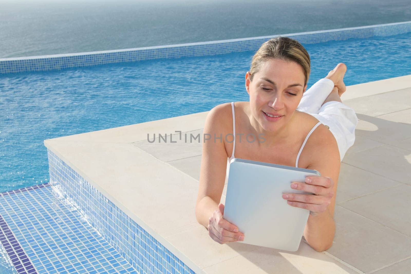 Woman using electronic tablet by swimming pool