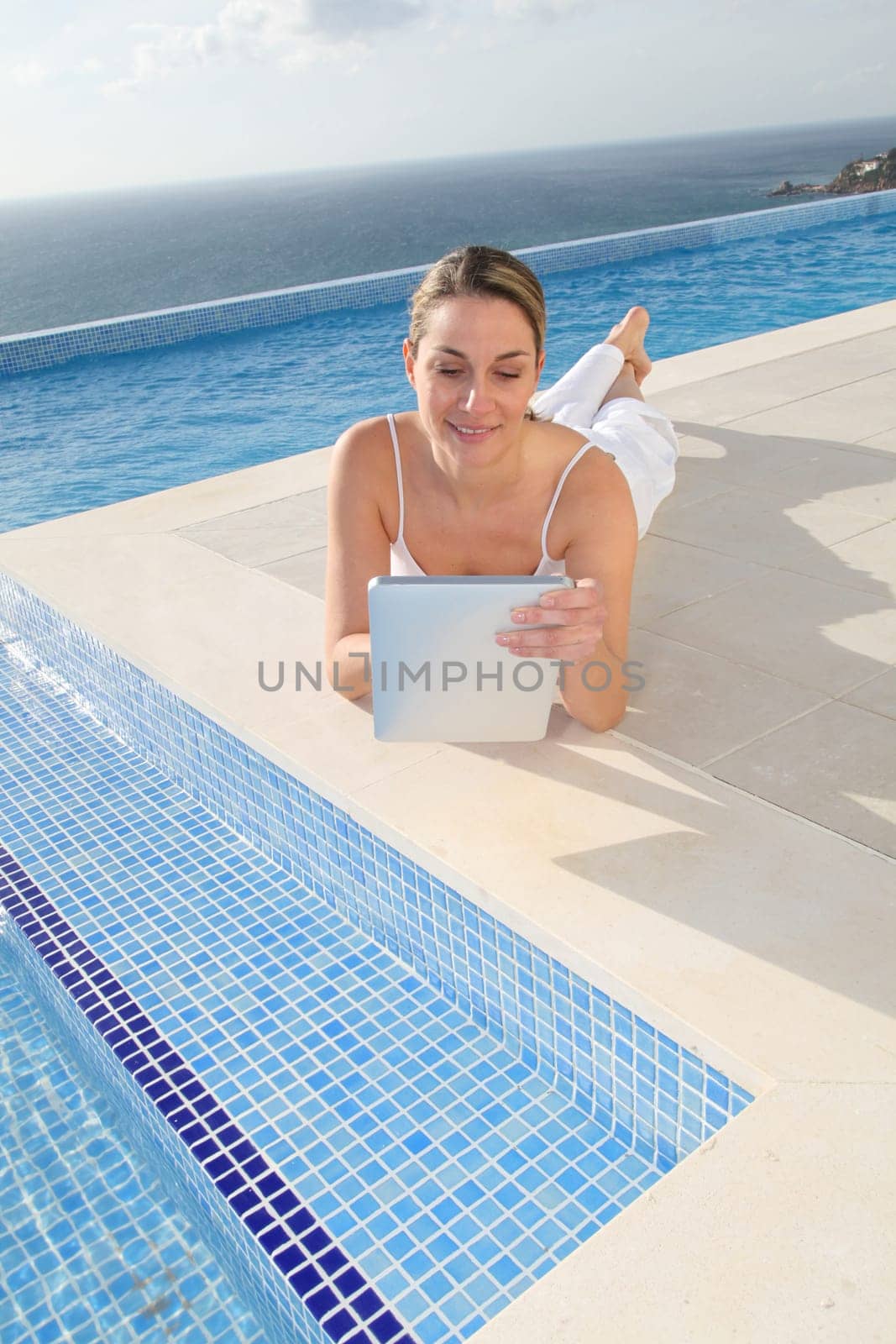 Woman using electronic tablet by swimming pool