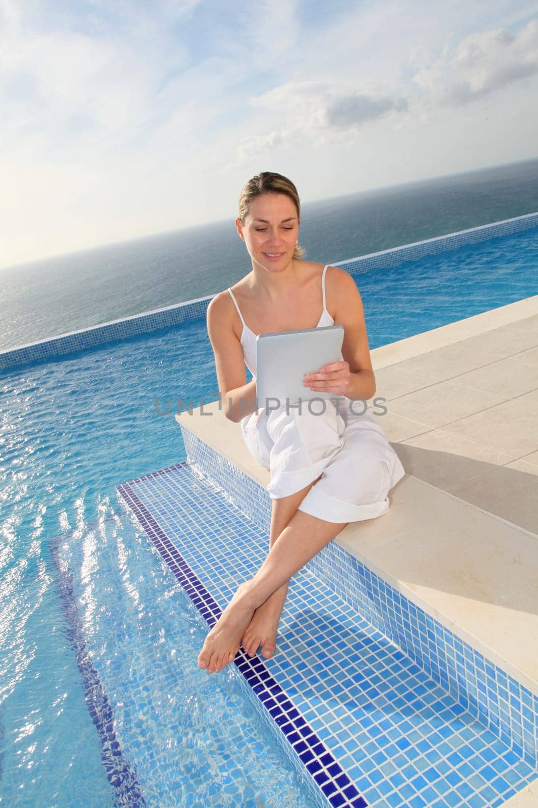 Woman using electronic tablet by swimming pool