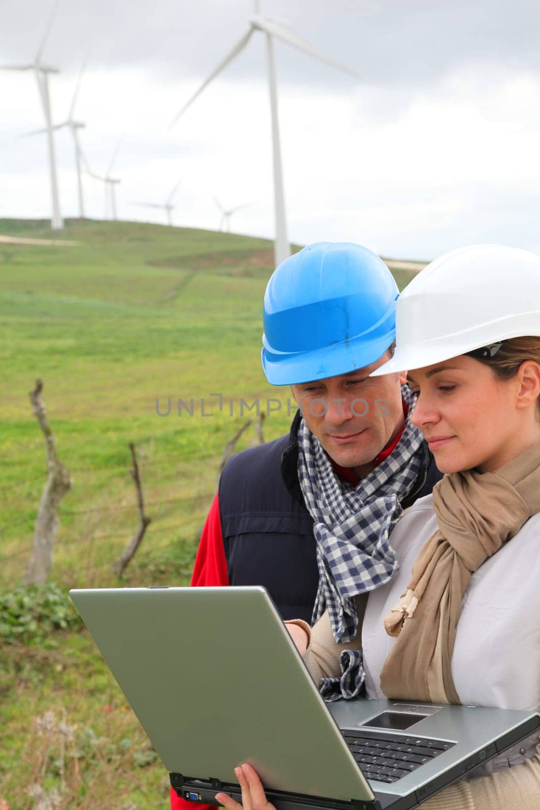 Engineers working by wind turbines field