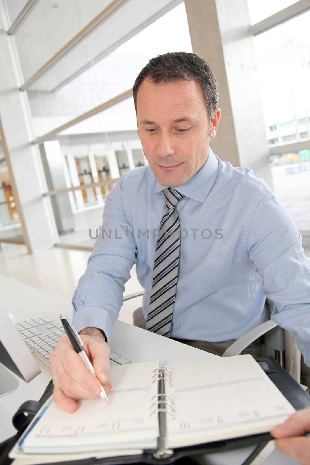 Portrait of salesman writing on agenda