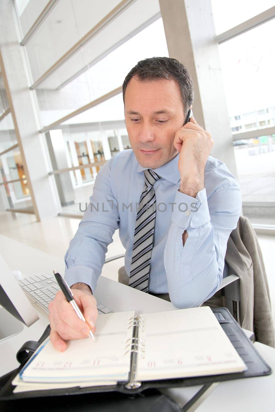 Businessman on the phone writing on agenda