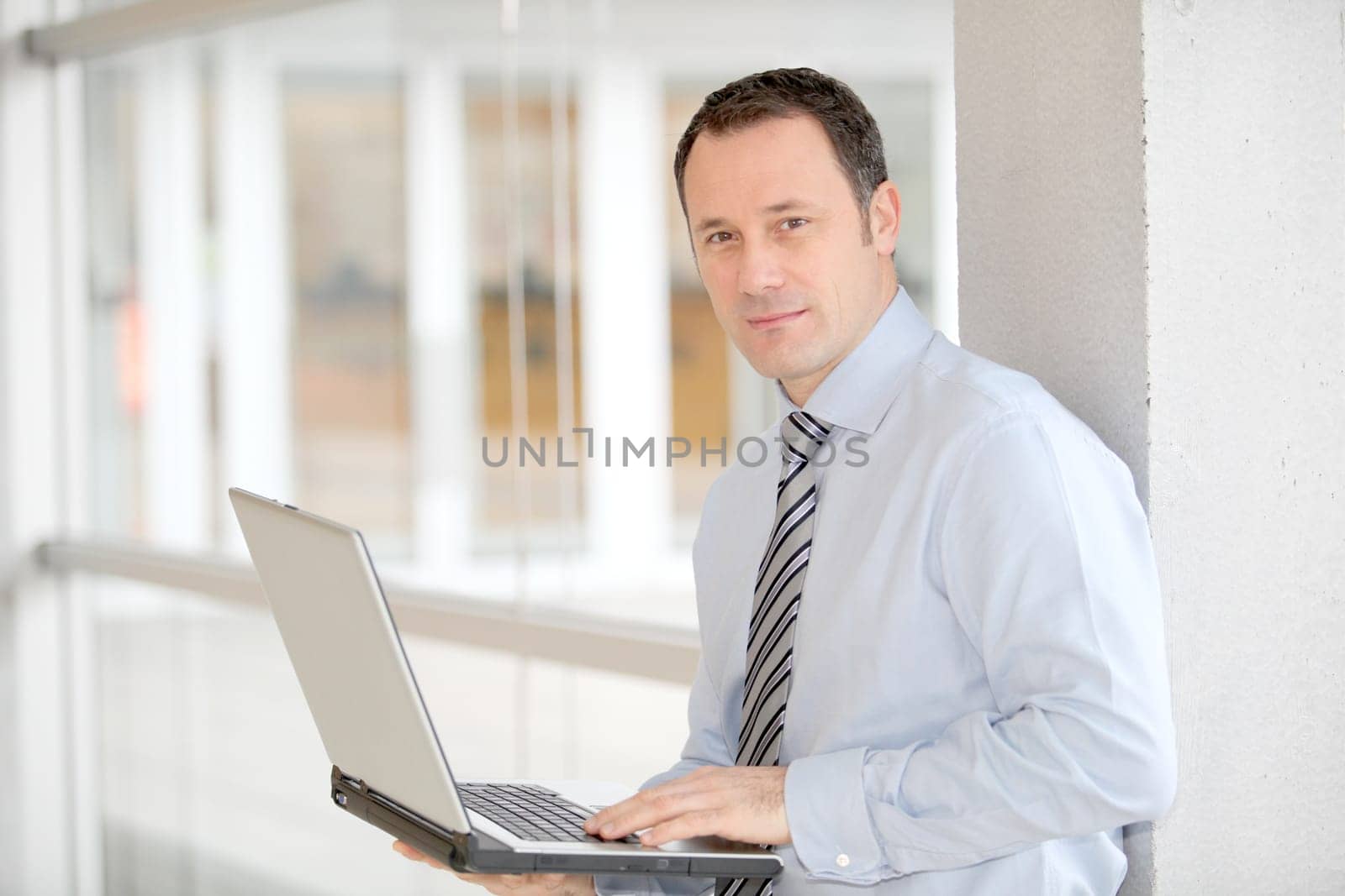 Businessman standing in hall with laptop computer