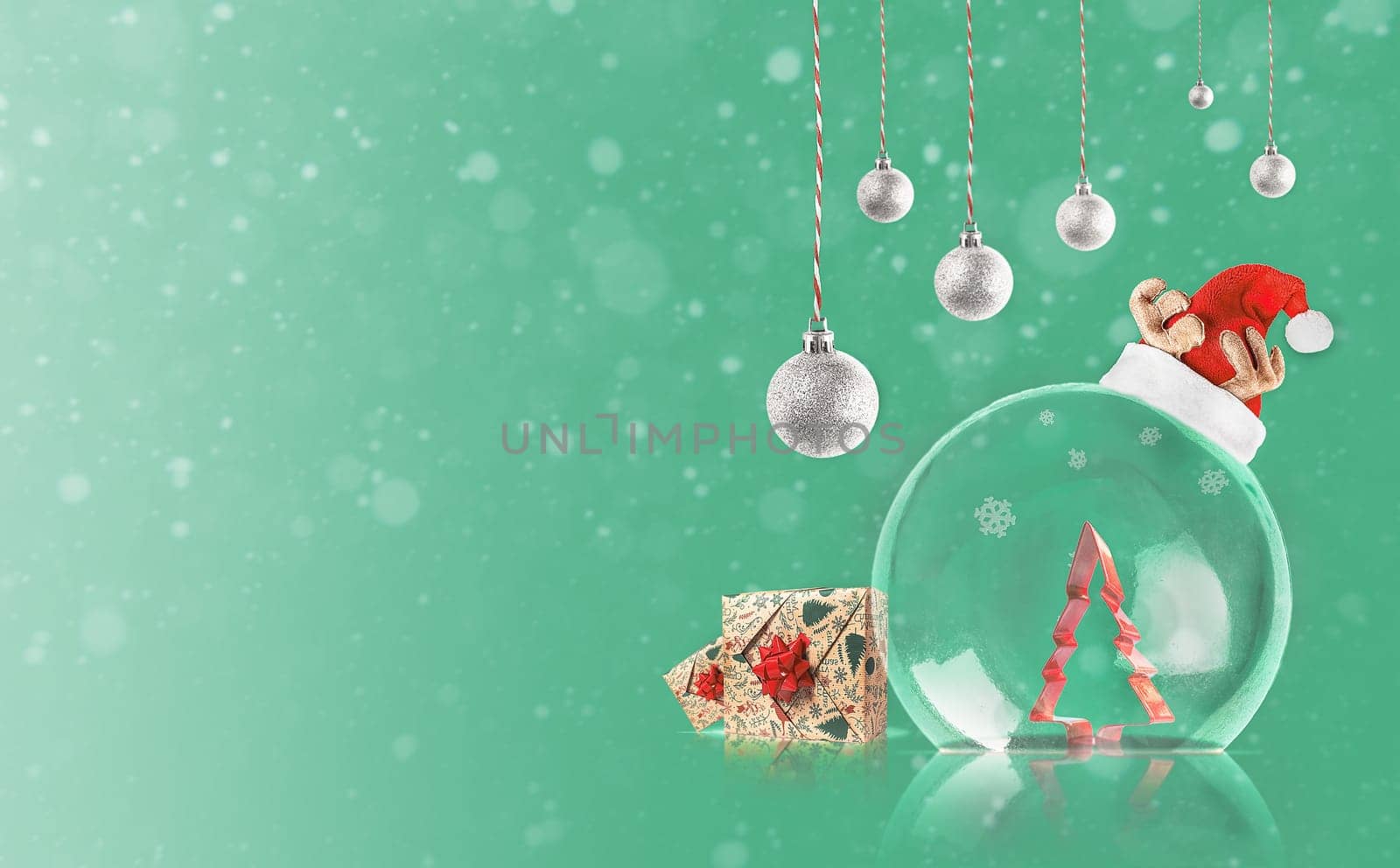 Transparent Christmas ball with Christmas tree inside. Silver decoration on green background with copy space. Merry Christmas.