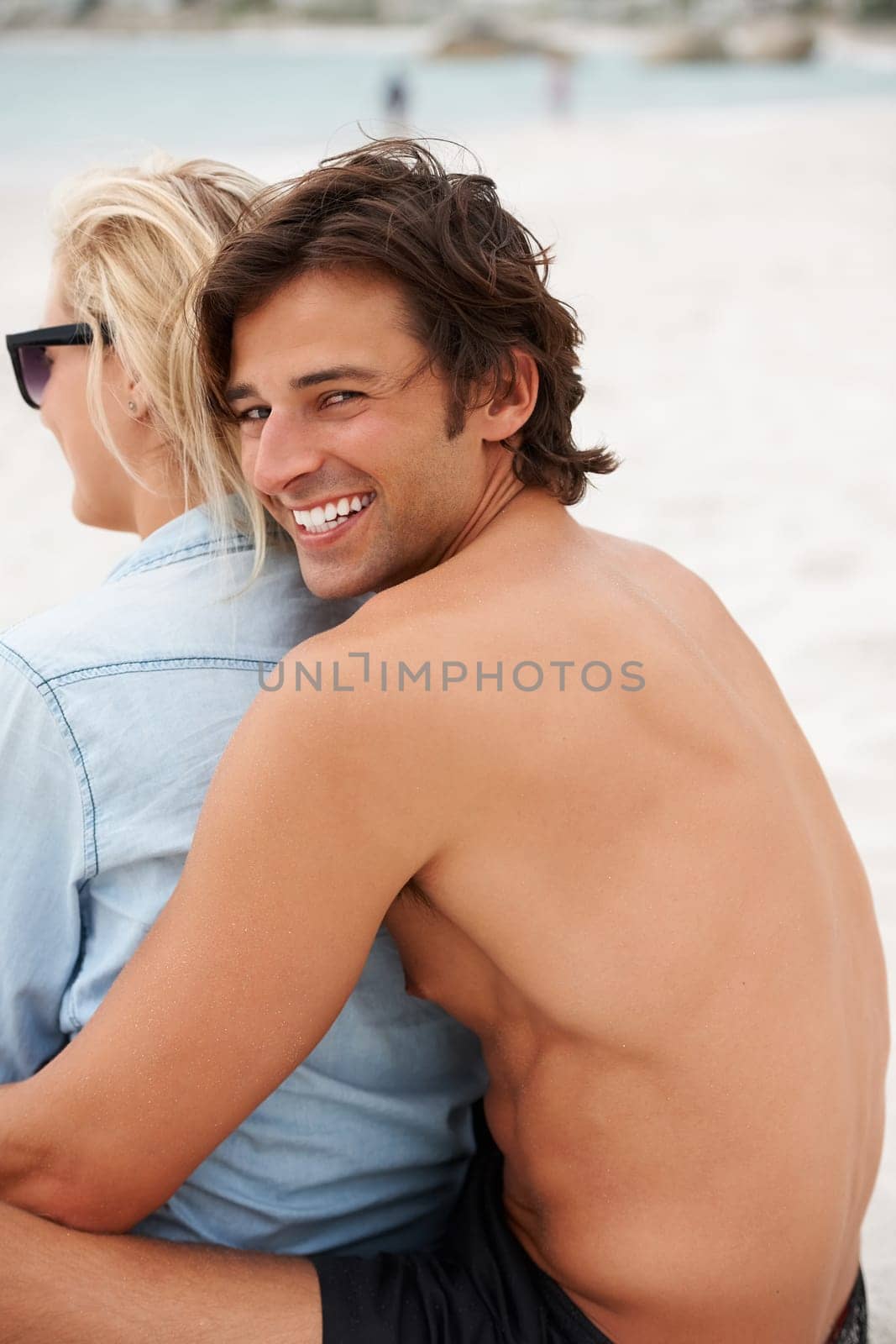 Couple, beach sand and sitting hug for holiday vacation, sunshine lovers or sea salt hair. Man, portrait and woman relax for partnership connection or ocean view, romantic or summer tropical travel by YuriArcurs