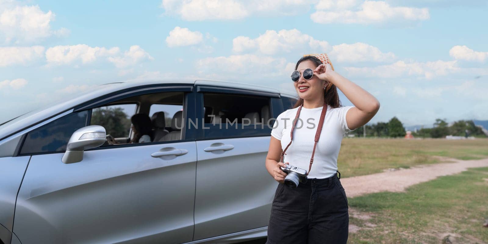 beautiful female smiling friends going on a trip while sticking head out of car in motion to see the view and take photos.