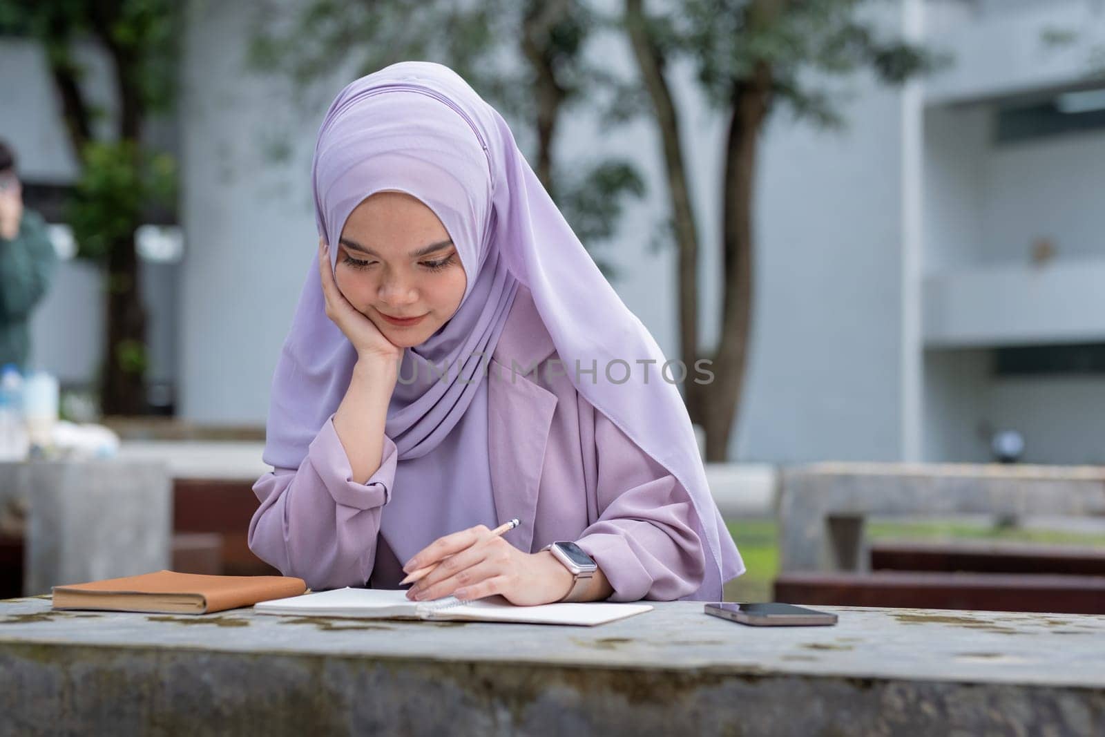 Beautiful Muslim college student girl taking note at university.