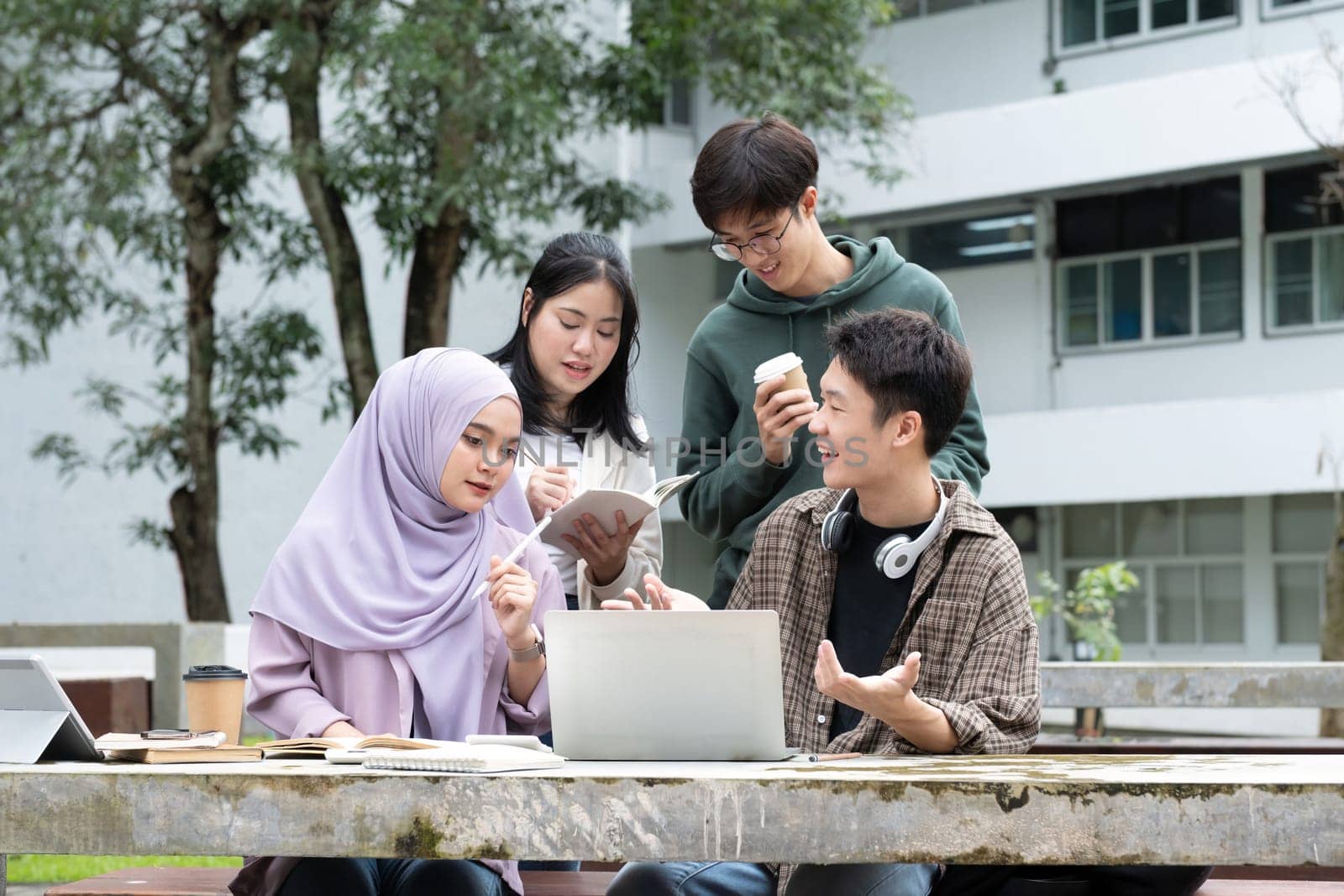 Student friendship concept with multiracial diverse classmate friend sitting together at campus college park. Millennial people having fun social gathering outside. Youth teenage and education.