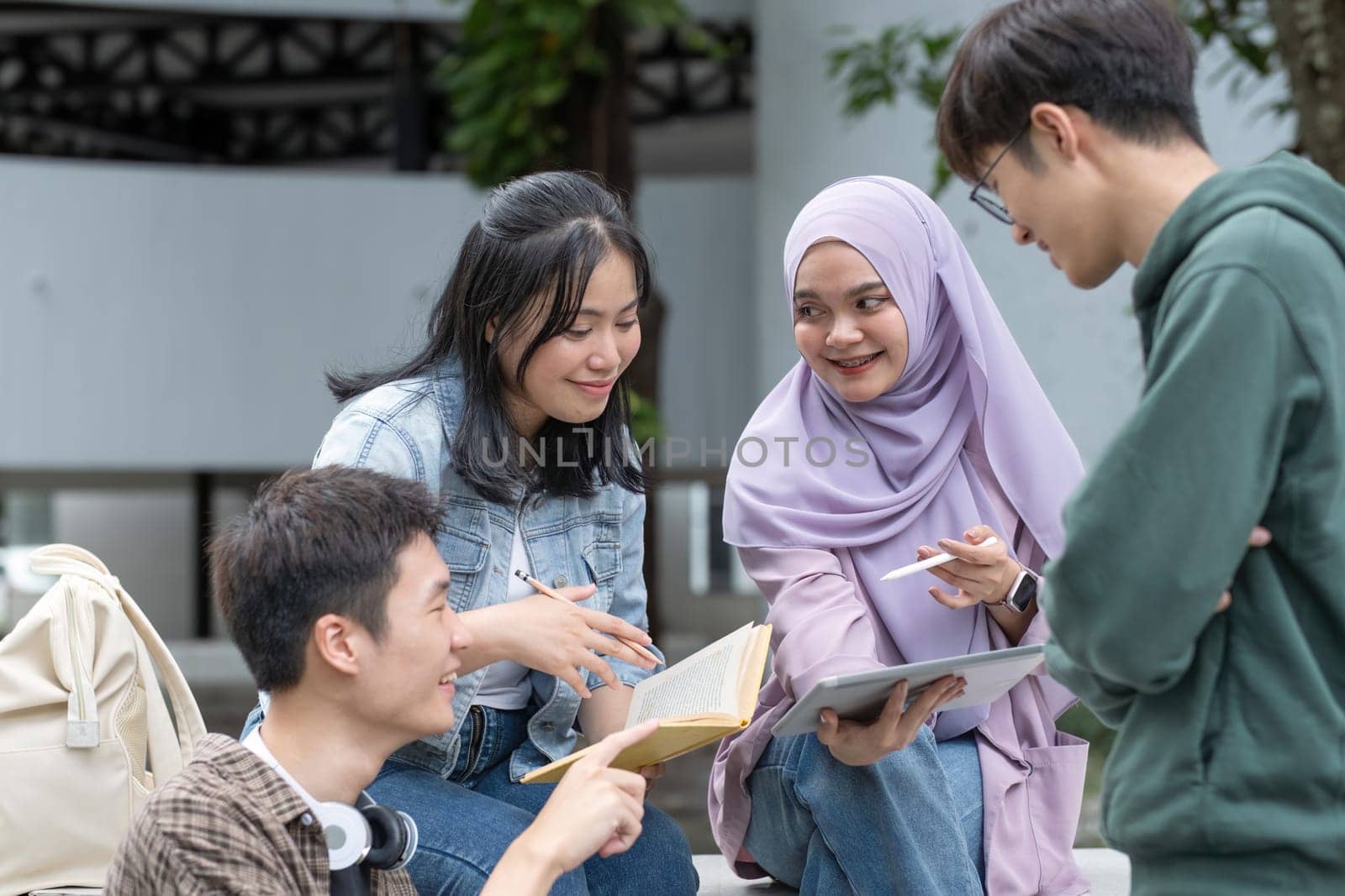 Student friendship concept with multiracial diverse classmate friend sitting together at campus college park. Millennial people having fun social gathering outside. Youth teenage and education.