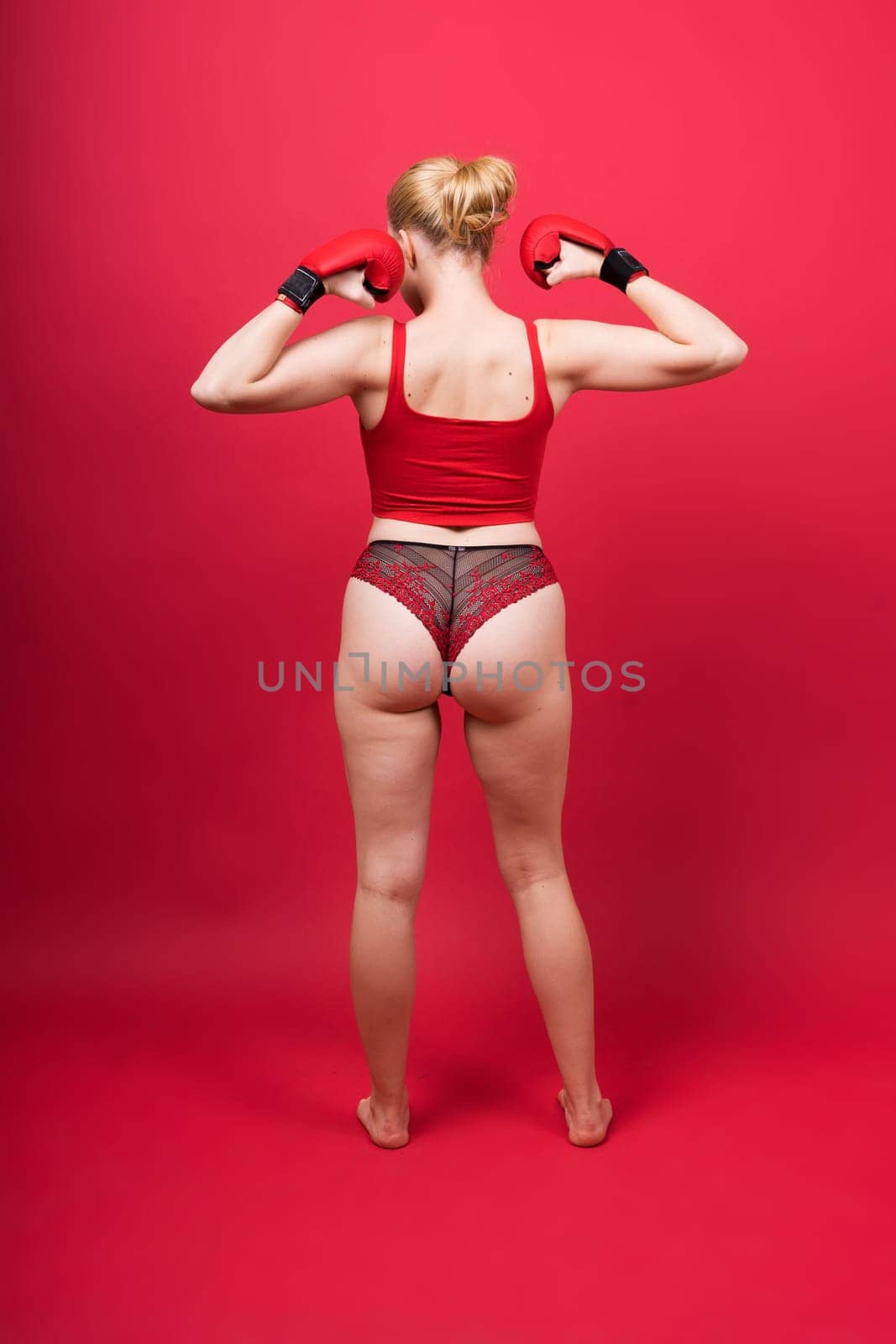 Image of seductive young woman boxer posing isolated on yellow red background in boxing gloves.