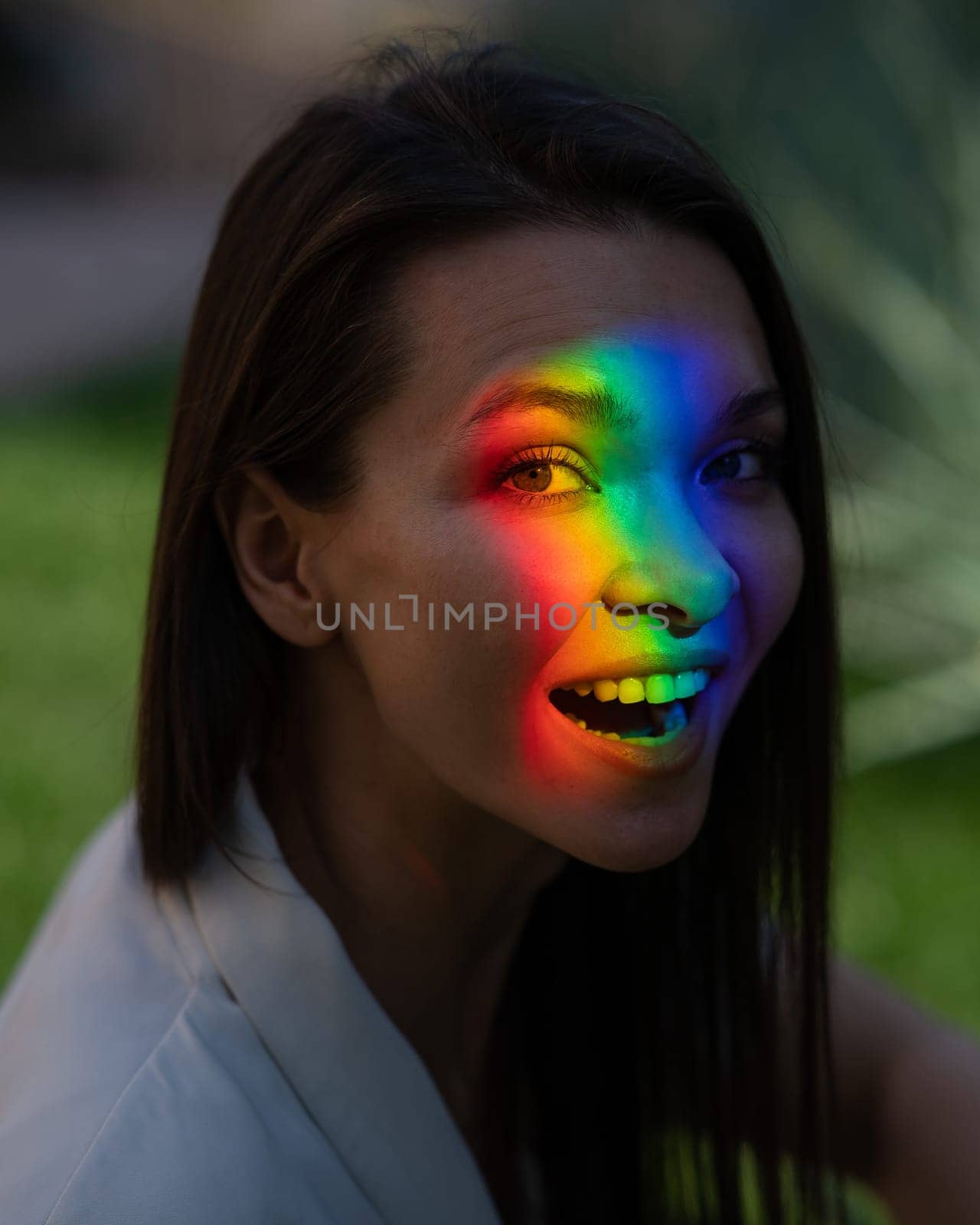 Portrait of caucasian woman with rainbow beam on her face outdoors