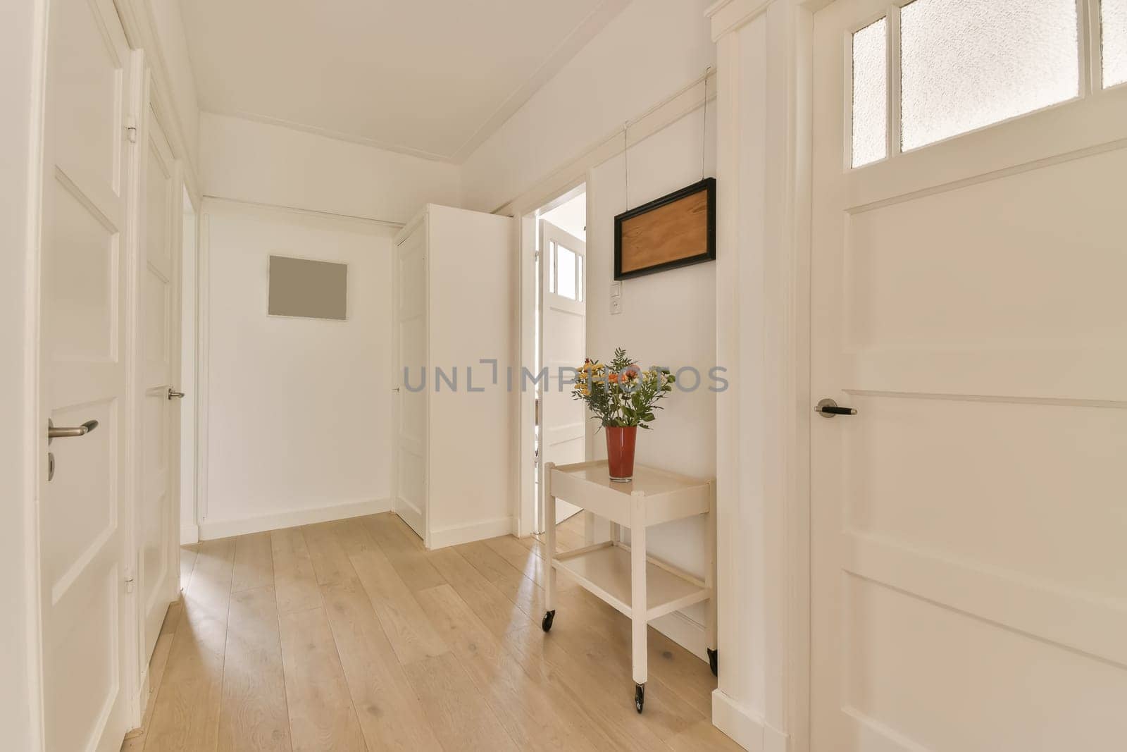 a hallway with white doors and a white table with by casamedia