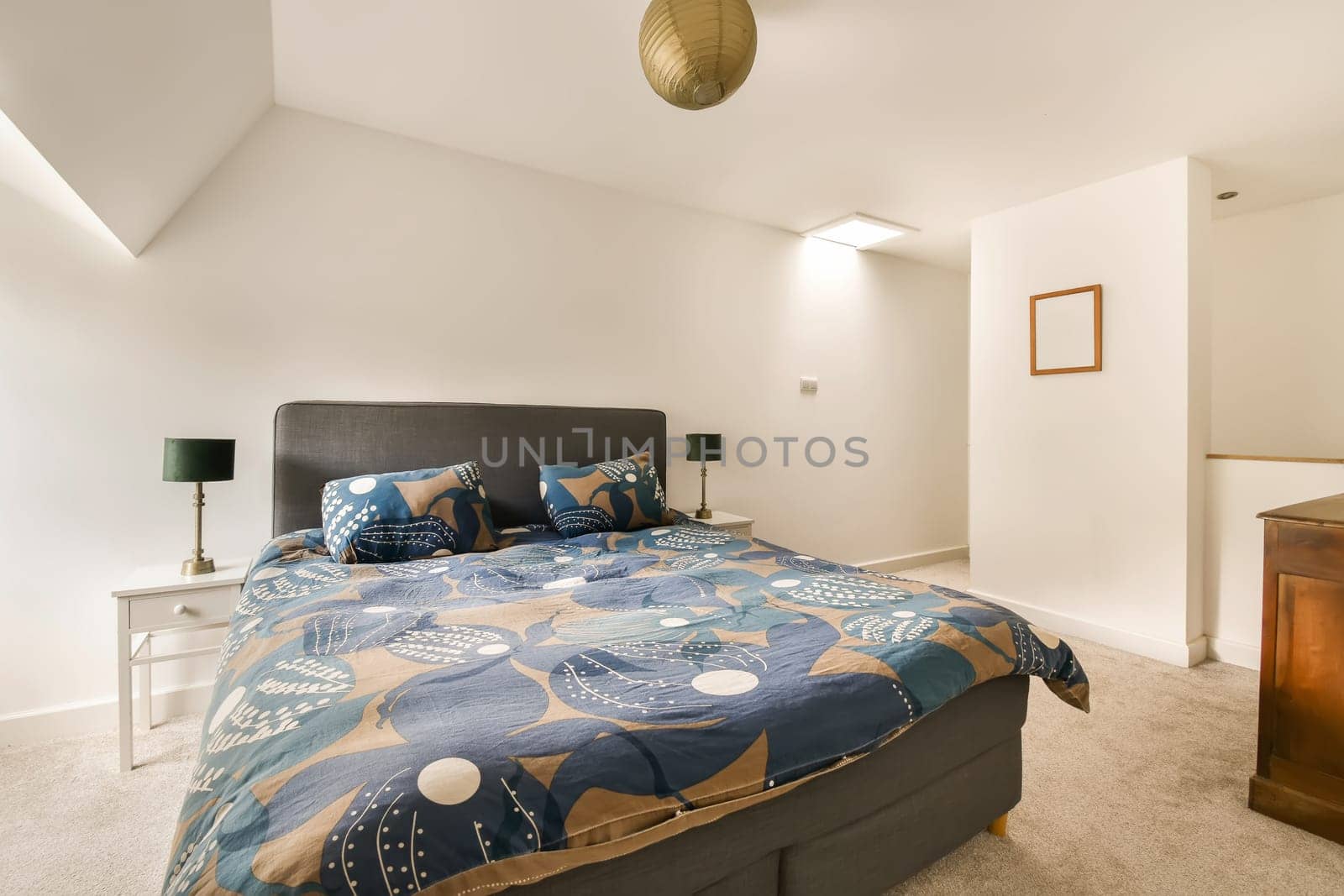 a bedroom with a bed, dresser and mirror on the wall above it is an image of a blue floral comforter
