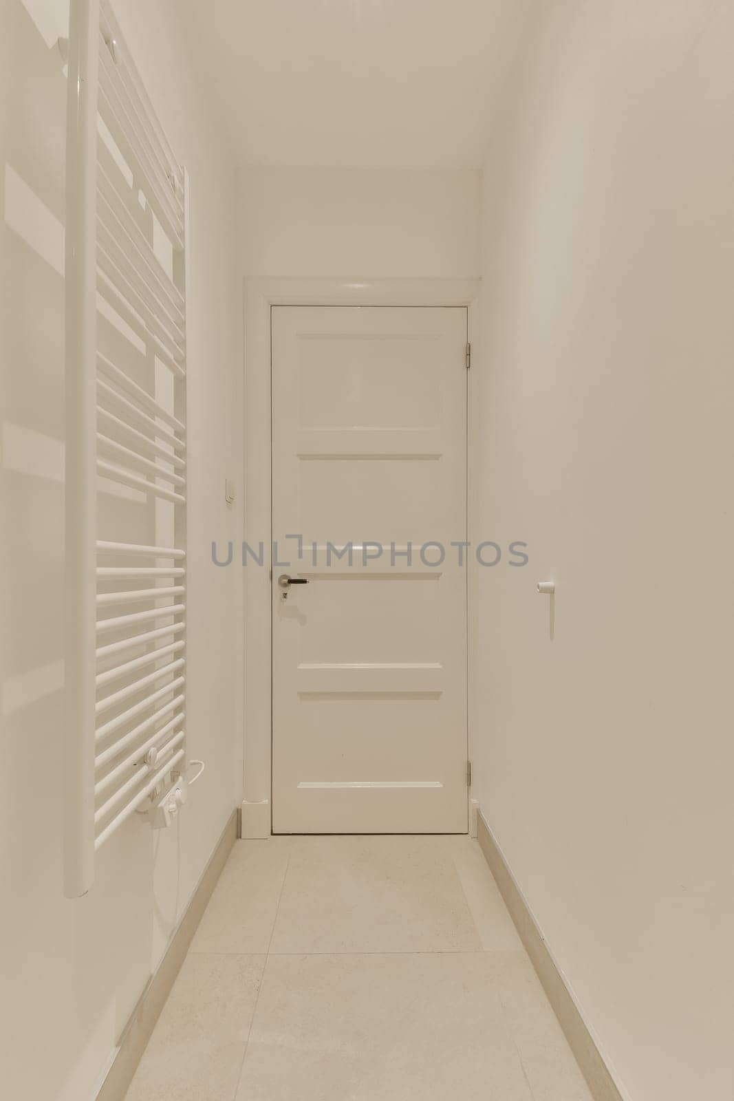 a long hallway with white walls and flooring on both sides, there is an open door in the middle