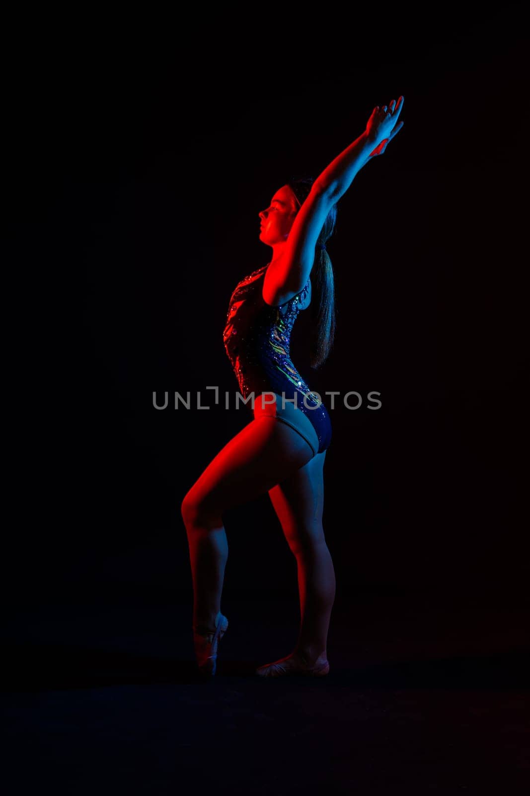 Sportive exercises, standing and stretching the hands. Beautiful muscular woman in indoors studio.