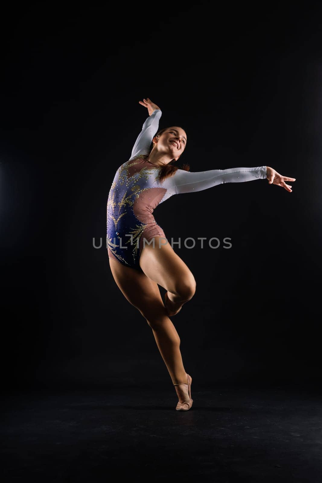 Sportive exercises, standing and stretching the hands. Beautiful muscular woman in indoors studio.