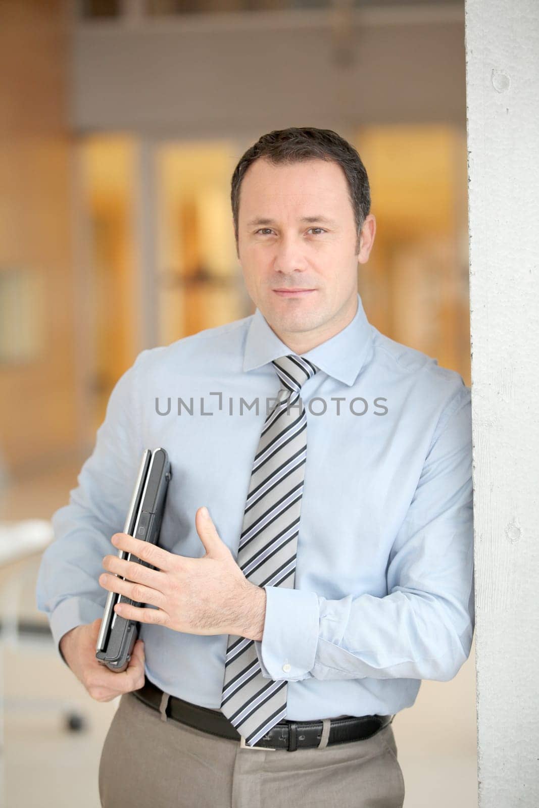 Businessman standing in hall with laptop computer