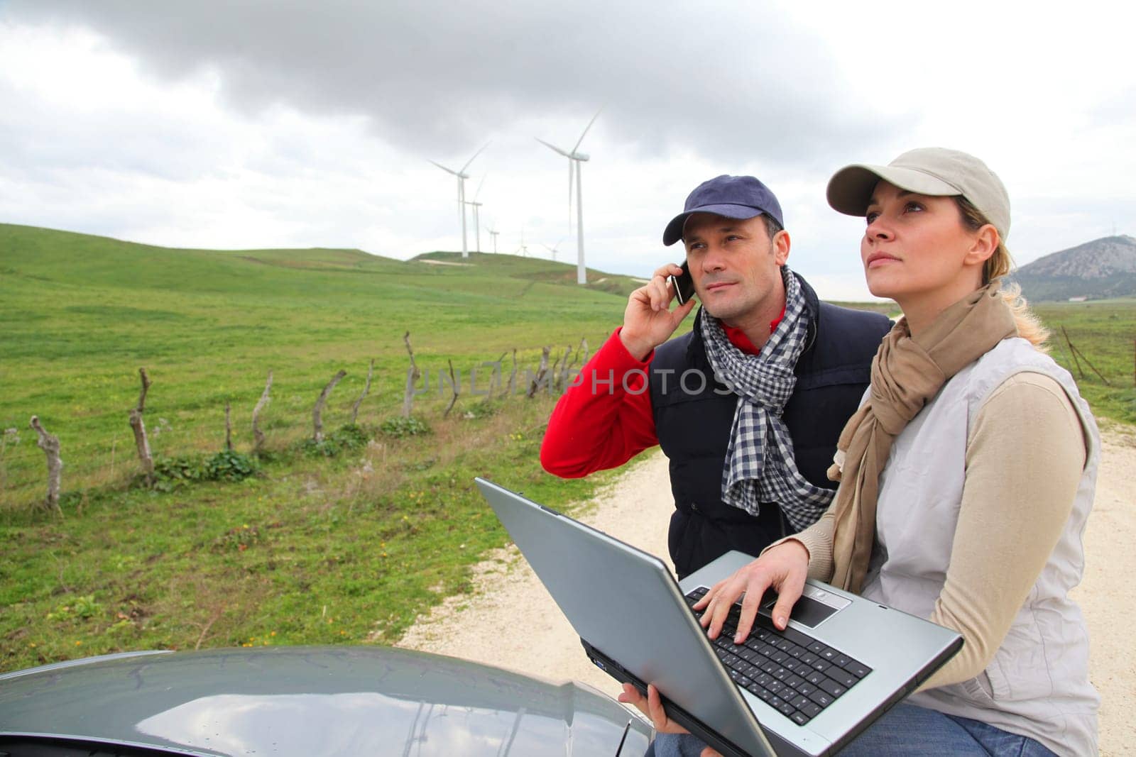 Engineers working by wind turbines field