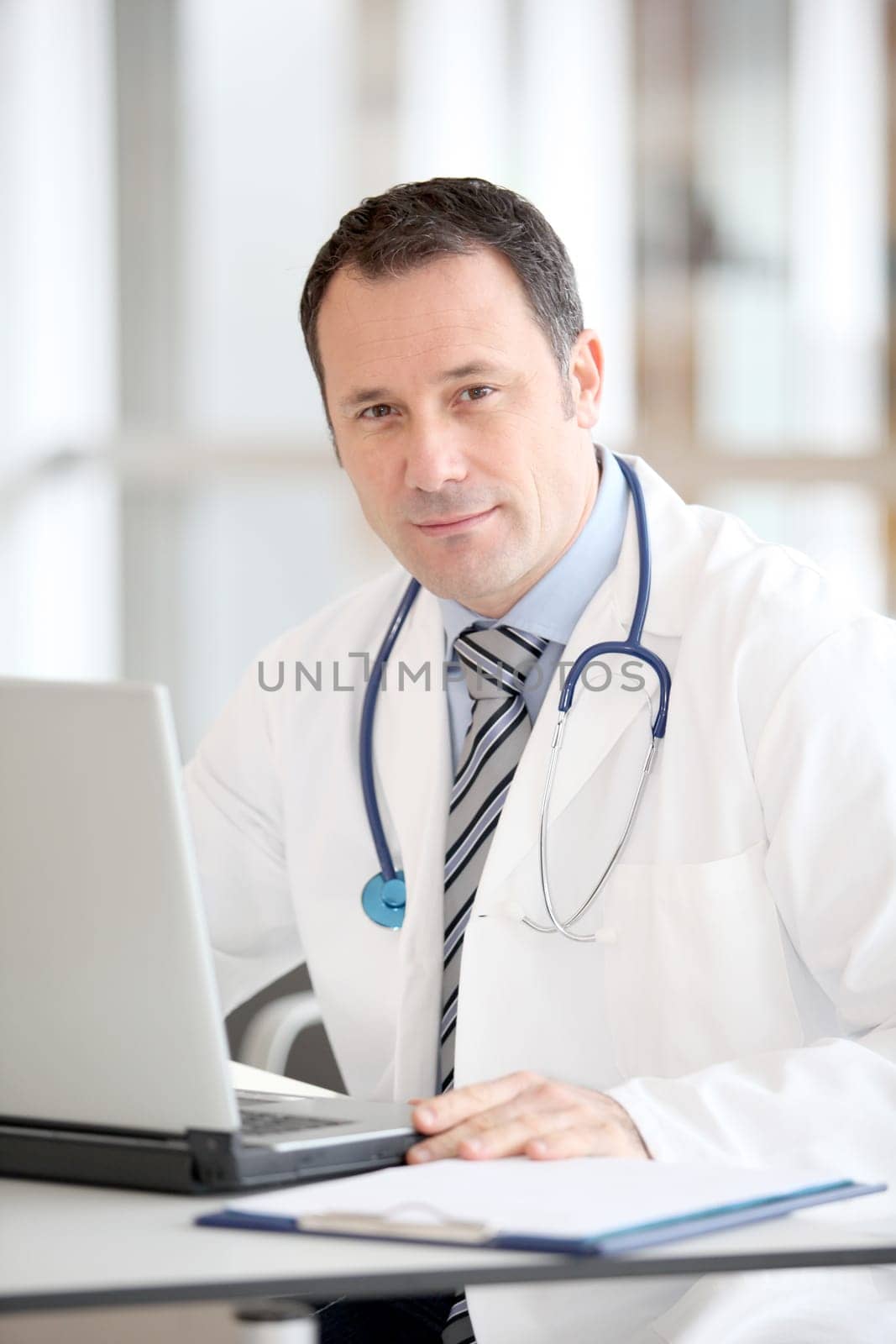 Doctor sitting at his desk with laptop computer