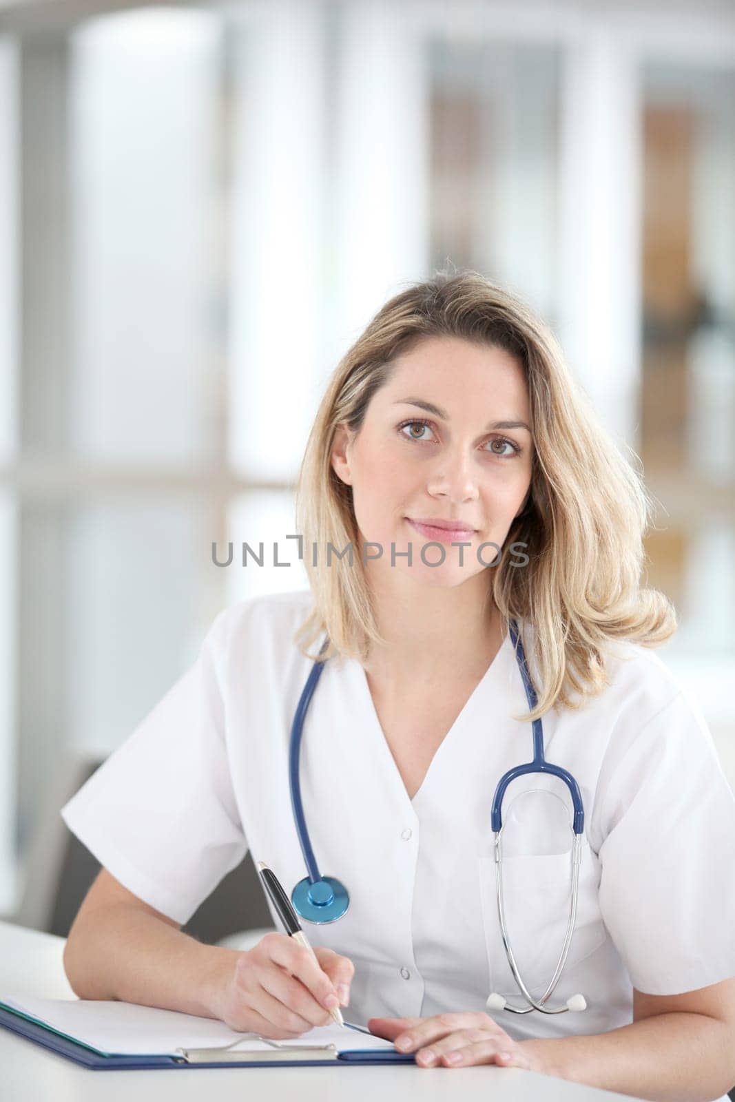 Beautiful nurse in hospital writing on notepad