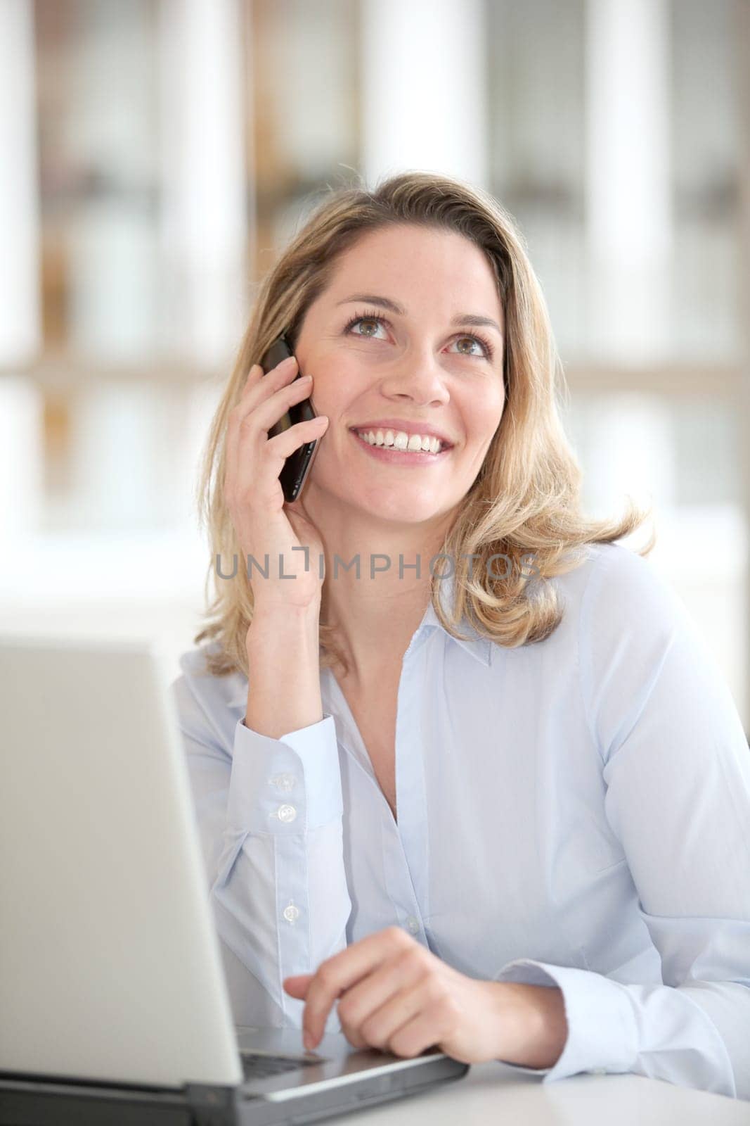 Smiling woman talking in the phone in the office