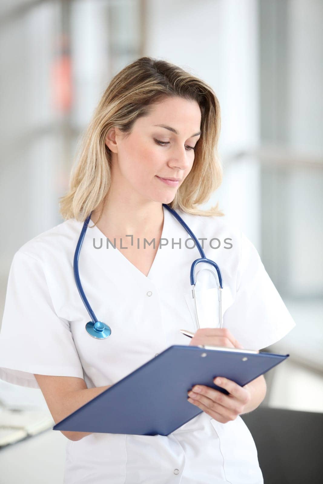 Beautiful nurse in hospital writing on notepad
